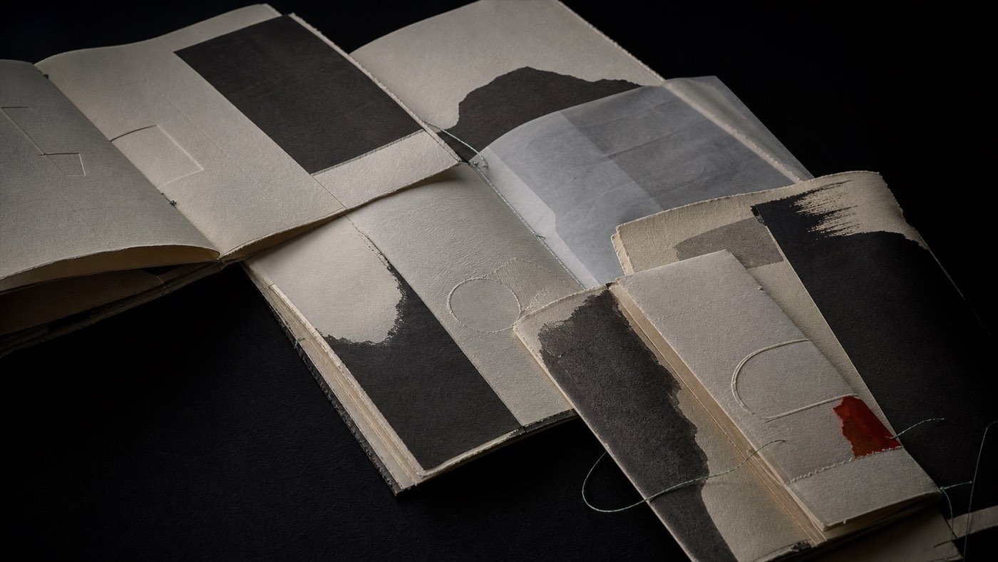 Pliegos editoriales de papel fibroso con campos de tinta negra, transparencias y encuadernación mínima.
